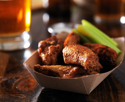 barbecue chicken wings with celery in basket on restaurant table