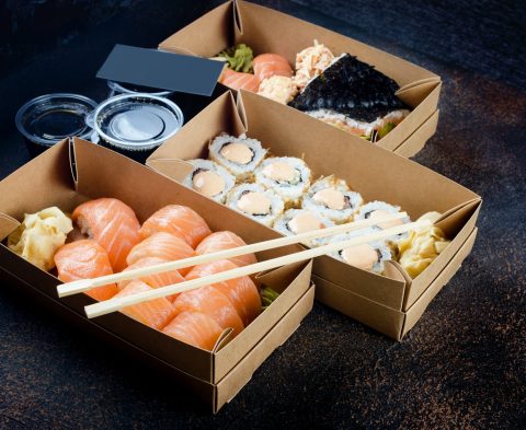 Tasty sushi rolls in disposable kraft paper boxes, sauces